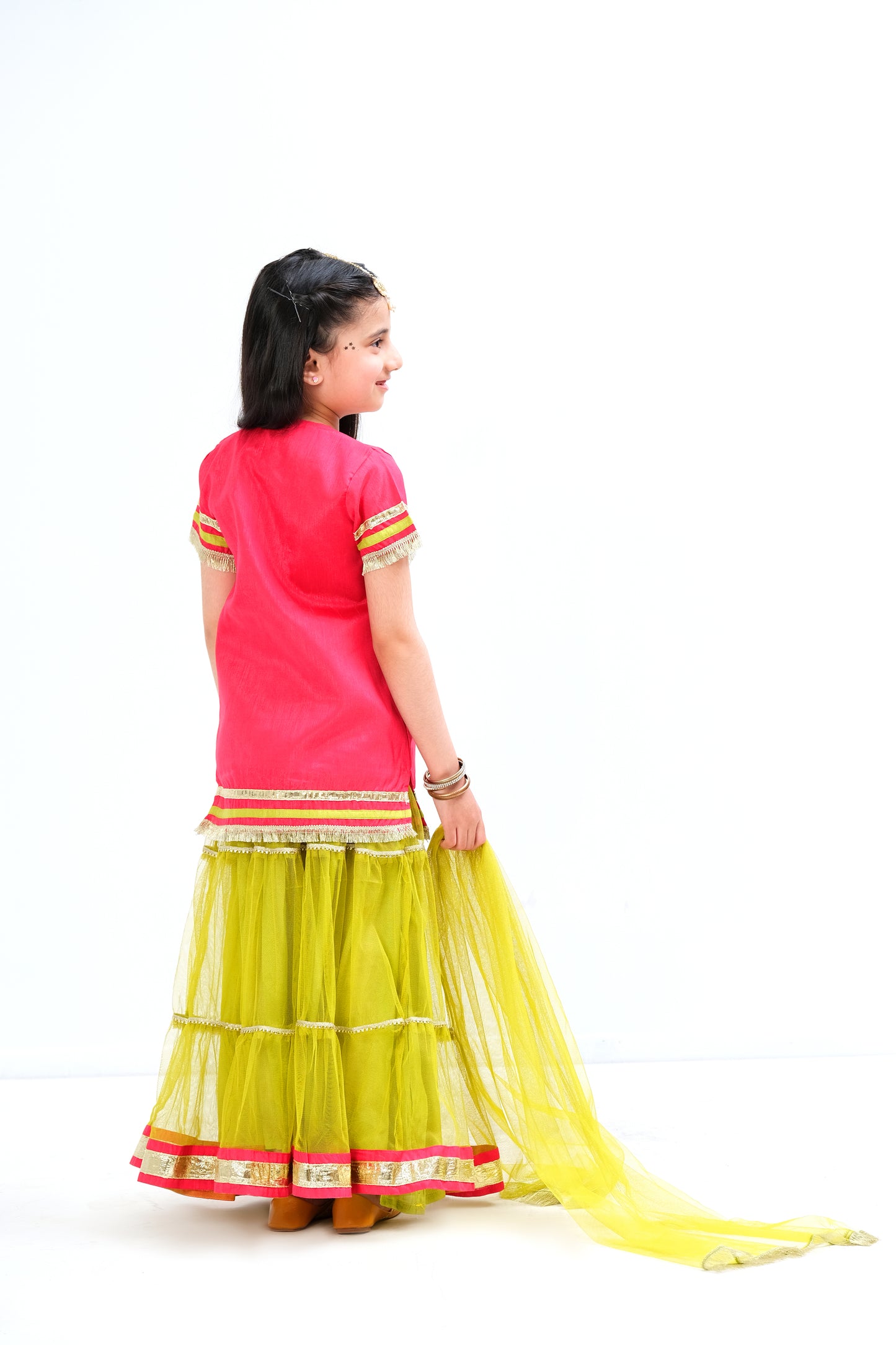 Raspberry color ethnic shirt with embroidery and laces. Bight green paneled lehnga with chatta patti border and golden lace on panels.